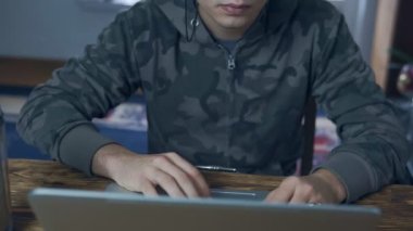 Genç erkekler evde bir dizüstü bilgisayarda çalışıyor. Uzak istihdam, freelancing