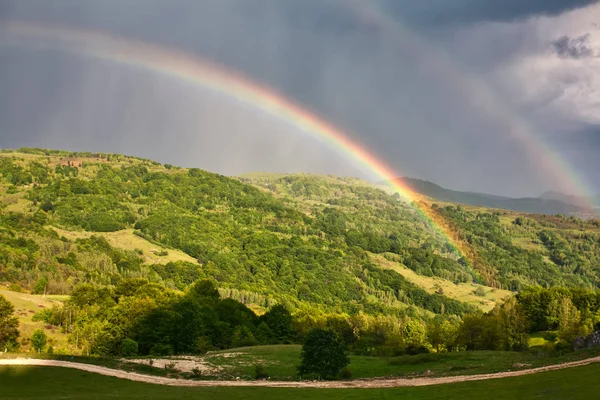 Hermoso valle de montaña con colinas verdes y gran arco iris —  Fotos de Stock