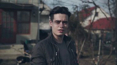 Genç adam gülümsüyor ve kameraya bakıyor. Mutlu yakışıklı genç bir adamın portresi açık. Kamera bakarak Genç Cool trendy adamın yüzünü yakın.