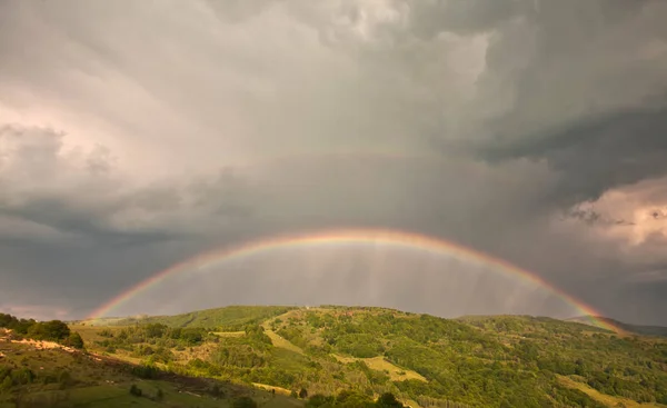Belo vale de montanha com colinas verdes e enorme arco-íris — Fotografia de Stock