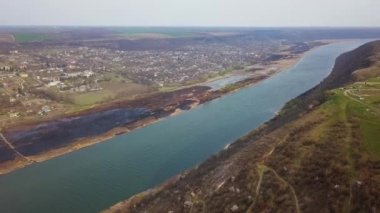 Nehir ve küçük köy üzerinde Arial görünümü. Bahar yangınları. Moldova Cumhuriyeti Dinyester Nehri.