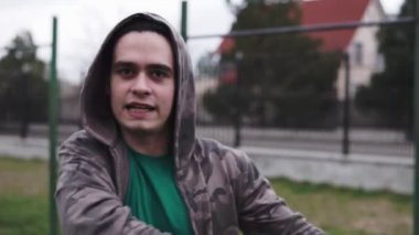 Genç bir adam kameraya bakar ve duygusal bir şey söyler.