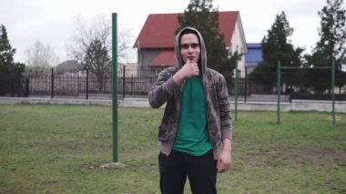 Genç bir adam kameraya bakar ve duygusal bir şey söyler.