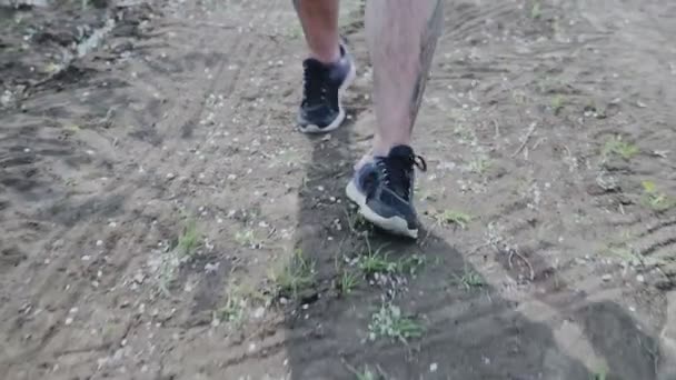 在阴天 穿着深色绑腿和灰色运动鞋 穿着白色花边的男孩腿的手持拍摄侧视图沿着公共公园的小径运行 — 图库视频影像