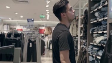 Genç adam bir dükkanda bir tezgâbe arıyor. O onun kumaş dokunmadan ve bir satış alanında fiyatları bakıyor