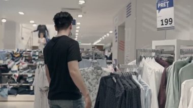 Genç adam bir dükkanda bir tezgâbe arıyor. O onun kumaş dokunmadan ve bir satış alanında fiyatları bakıyor