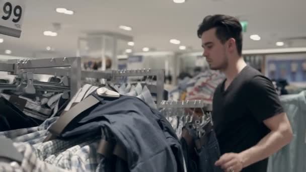 Молодий Хлопець Шукає Одяг Магазині Він Торкається Його Тканини Дивиться — стокове відео
