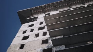 Mavi, bulutlu gökyüzü arka plan üzerinde sarı vinç yakınında yüksek bina bitmemiş inşaat alt görünümü. İnşaat aşamasındaki yüksek katlı bina