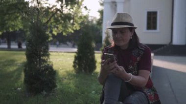 bir şapka genç esmer bir şehir yaz parkında bir cep telefonu kullanıyor