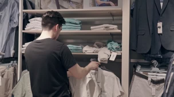 Jonge Kerel Zoek Naar Kleding Een Winkel Hij Het Aanraken — Stockvideo