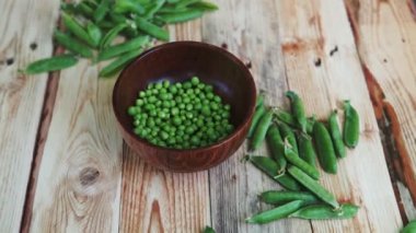 kahverengi çanak, ahşap masa üzerinde kadın el depod yeşil bezelye closeup.