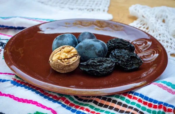 Fresh and dried prunes whit walnuts on plate. Natural food. Outdur composition. Close up. — Stock Photo, Image