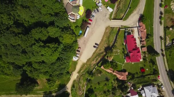 Drone survole la forêt verte et la petite ville dans une région montagneuse ensoleillée en saison estivale. Carpatiens montagnes, Roumanie .