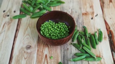 kahverengi çanak, ahşap masa üzerinde kadın el depod yeşil bezelye closeup.