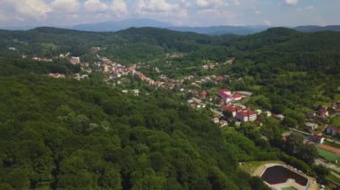 Drone yaz sezonunda Dağlık alan güneşli gün yeşil orman ve küçük şehir üzerinde uçar. Carpatians Mountains, Romanya.