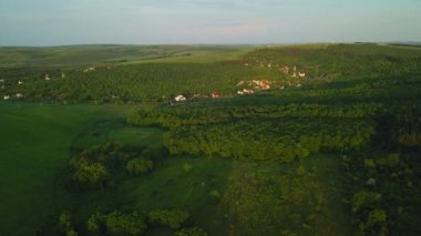 Yeşil kırsal tepelerin, köy evlerinin, baharda tarım arazilerinin üzerinde uçuyorlar. Hava 4k dron görüntüsü