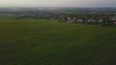 Yeşil kırsal tepelerin, köy evlerinin, baharda tarım arazilerinin üzerinde uçuyorlar. Hava 4k dron görüntüsü