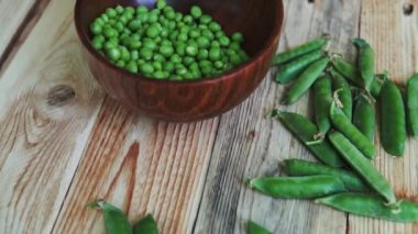 kahverengi çanak, ahşap masa üzerinde kadın el depod yeşil bezelye closeup.