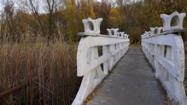 Kamera sonbahar parkında taş köprü boyunca geçer