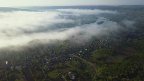 Slowly looking up over a river Dniester and small village covered in mist in the morning sun. — Stock Video