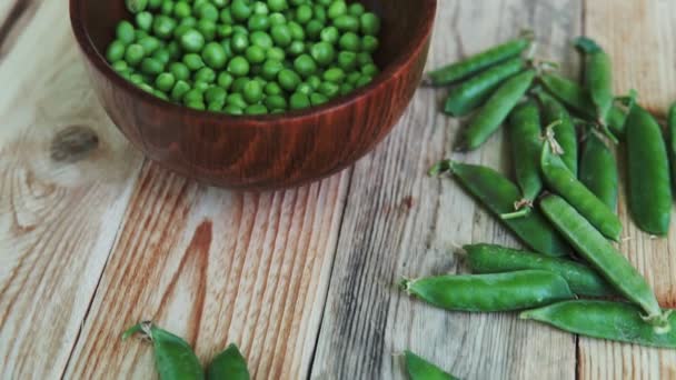 Primer plano guisantes verdes en plato marrón, sobre mesa de madera . — Vídeo de stock