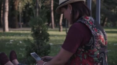 bir şapka genç esmer bir şehir yaz parkında bir cep telefonu kullanıyor