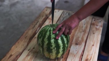 Yaz için ahşap rustik tahta taze meyve olgun karpuz kesmek için mutfak bıçağı kullanarak kadının çekim elleri kadar yakın