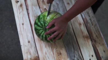 Yaz için ahşap rustik tahta taze meyve olgun karpuz kesmek için mutfak bıçağı kullanarak kadının çekim elleri kadar yakın