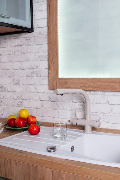 El vaso está lleno de agua del grifo en la cocina —  Fotos de Stock