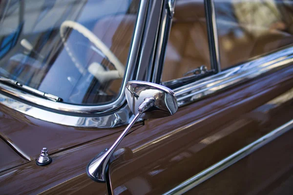 Close up of shiny chrome rear view mirror of classic car.
