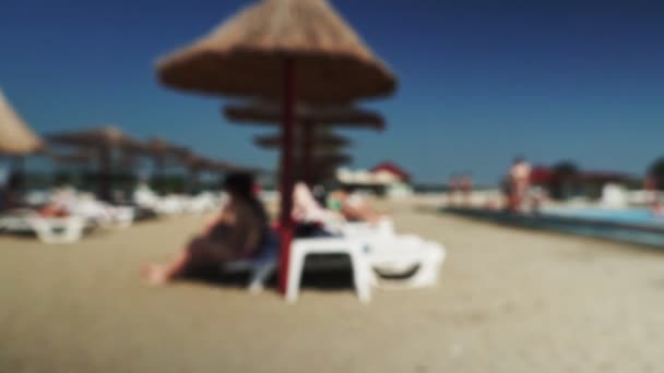 晴れた日にデッキチェア付きの砂のトロピカルビーチ。ぼやけた画像. — ストック動画
