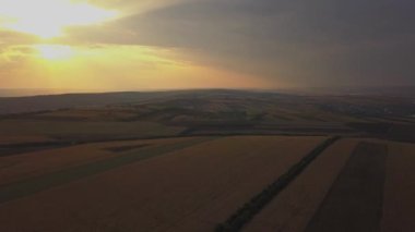 Dramatik sonbahar günbatımı manzara üzerinde Aerial View Drone Uçuş. Küçük bir köy çayırları, turuncu tepeleri kuşattı. 4k