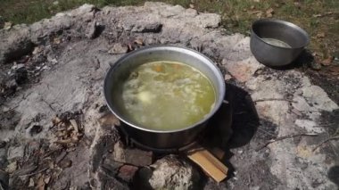 yaz günü / akşam. yolculukta turist tatil. ateşte bir tencerede pişmiş kulak, yangın taşlardan yapılır. ateş odun üzerinde yanıyor.