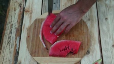 Adam tahta bir masada karpuz kesti.
