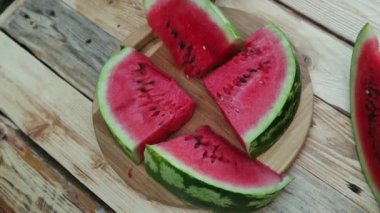 İnsanlar ahşap masa, üst görünümü üzerinde sulu olgun karpuz kesilmiş parçaları alır.