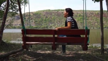 Bir adam ve bir kadın ahşap salıncak dinlenmek oturup nehir manzara hayran