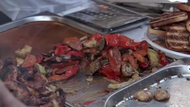 O ponto de vista das filmagens de vídeo filmou um monte de churrasco grelhado em panelas de aquecimento. Carne de churrasco, bacon, asa de frango, salsicha, carne, carne de porco e legumes. Comida de rua — Vídeo de Stock