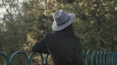 Duygusal açıdan mutlu, uzun saçlı, şapkalı ve kameraya gülümseyen esmer kadını yakından çek. Kuaförden sonra mükemmel makyajlı, parkta poz veren güzel bir model. Moda ve güzellik kavramı.