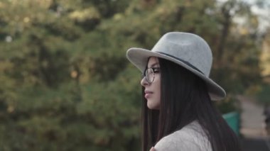 Duygusal açıdan mutlu, uzun saçlı, şapkalı ve kameraya gülümseyen esmer kadını yakından çek. Kuaförden sonra mükemmel makyajlı, parkta poz veren güzel bir model. Moda ve güzellik kavramı.