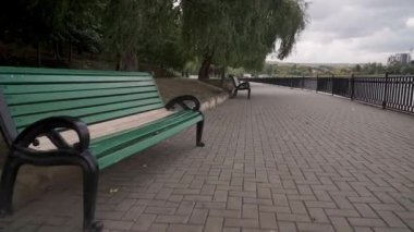 Şehir parkındaki boş bir göl kordonunun önünde kamera hareketi. Bulutlu sonbahar günü.