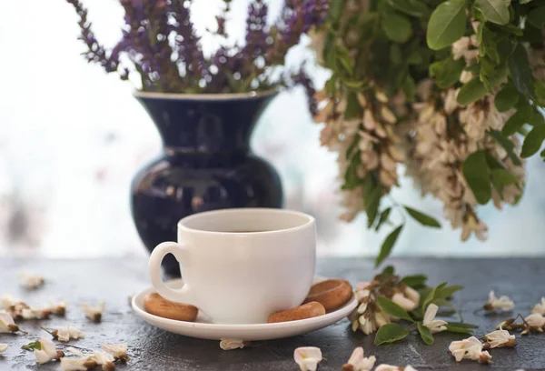 コーヒーとアカシアのクローズアップのカップ 背景にはコーヒーとアカシアの花が — ストック写真