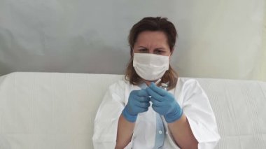 Doktor aşıyı şırıngaya koyar. Cam şişe bir teknisyenin elinde. Tedavisi olan bir şişe silikon eldivenlerde el tutar. Tedavide bir atılım. Aşı muayeneleri. Salgın.