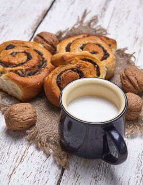 Reçelli ev yapımı çörekler, cevizli ve sütlü eski ahşap masada servis ediliyor.