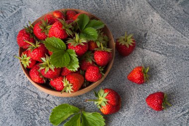 Mavi taş arka planda ahşap bir kasede kırmızı çilekler.