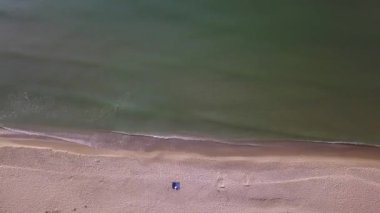 Sahilin havadan görünüşü ve denizin dalgaları altın kumun üzerine sıçrıyor.