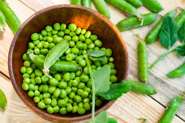 Primer Plano Guisantes Verdes Plato Marrón Sobre Mesa Madera —  Fotos de Stock