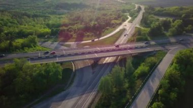 Akşam trafiği üzerinde uçan bir insansız hava aracı. Otoyol ve kamyonlar, kavşak, iki katlı yol ayrımı. Çevre yolu, hat.