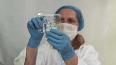 Aşı virüsü. Coronavirus konsepti. Doktor elinde bulanık mavi bir arka plan üzerinde aşısı olan bir ampul tutuyor. Virüs koruması. Soğuk algınlığı ve grip.