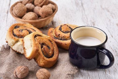 Reçelli ev yapımı çörekler, cevizli ve sütlü eski ahşap masada servis ediliyor.