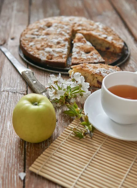 Homemade pie with cherries and apples white cup of tea on a dark rustic wooden board background. Rustic style food